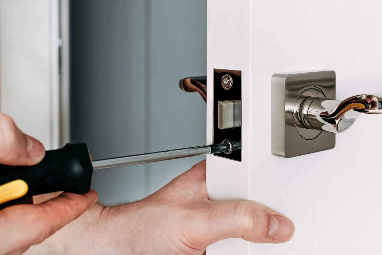 un-serrurier-repare-la-serrure-de-porte-dans-la-chambre-un-serrurier-fixant-la-serrure-avec-un-tournevis-noir